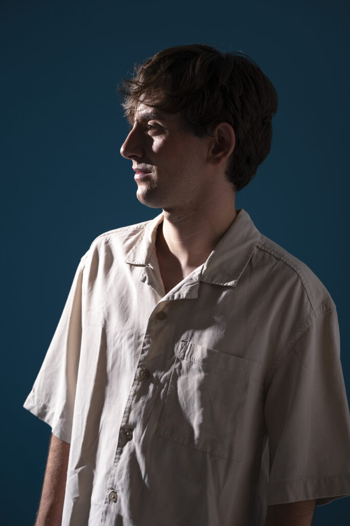 Retrato de hombre joven , mirando con expresión intensa frente a fondo oscuro.