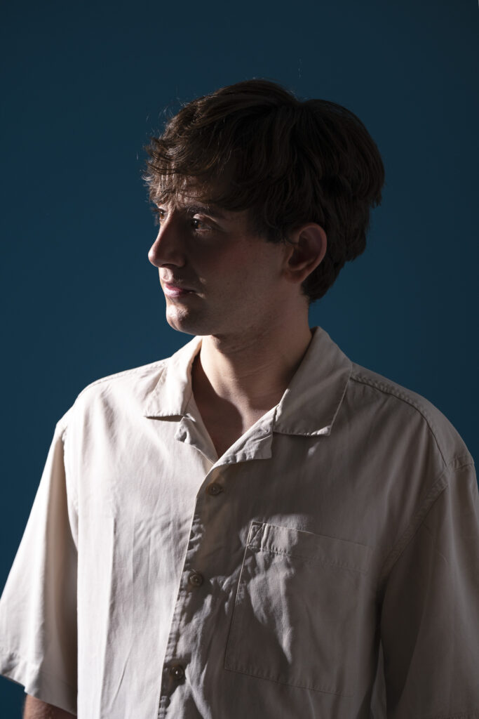 Retrato de hombre joven , mirando con expresión intensa frente a fondo oscuro.