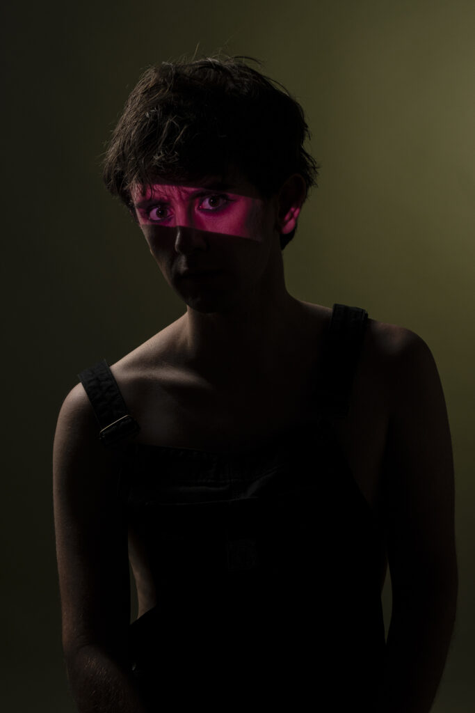 Retrato de hombre joven, mirando con expresión intensa frente a fondo oscuro.