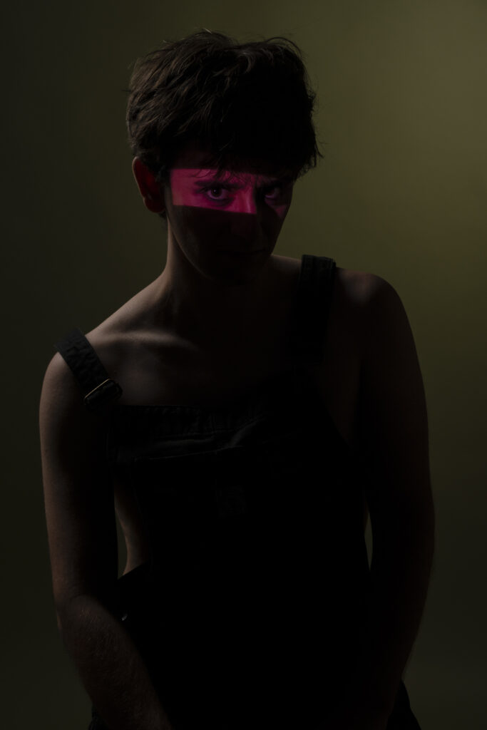 Retrato de hombre joven , mirando con expresión intensa frente a fondo oscuro.