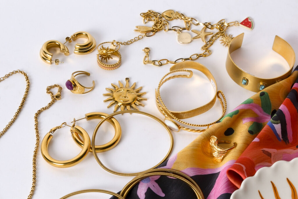 Primer plano de joyas artesanales sobre superficie neutra, con luz suave resaltando texturas y detalles.