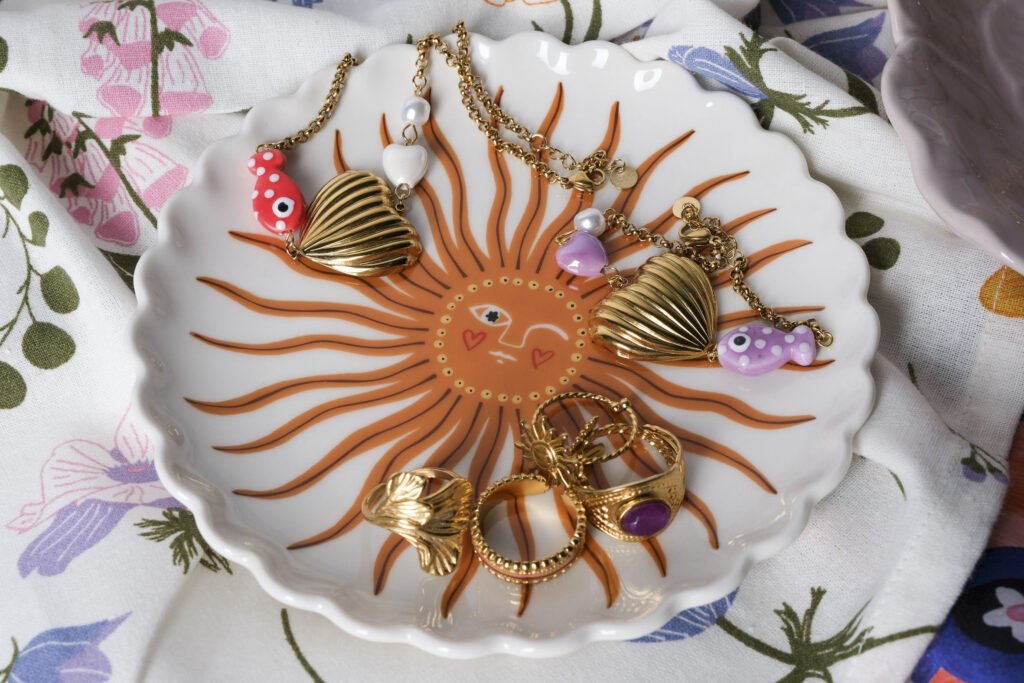 Primer plano de joyas artesanales sobre superficie neutra, con luz suave resaltando texturas y detalles.