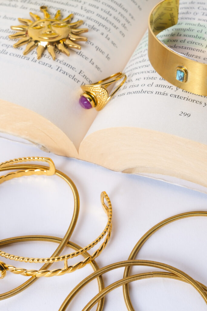 Primer plano de joyas artesanales sobre superficie neutra, con luz suave resaltando texturas y detalles.