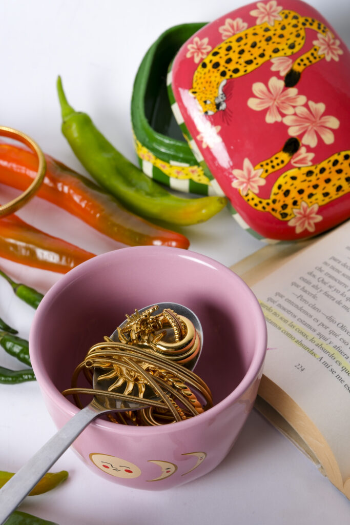 Primer plano de joyas artesanales sobre superficie neutra, con luz suave resaltando texturas y detalles.