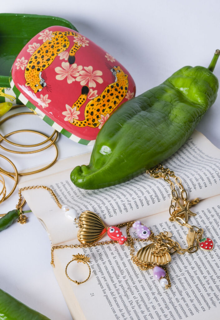 Primer plano de joyas artesanales sobre superficie neutra, con luz suave resaltando texturas y detalles.